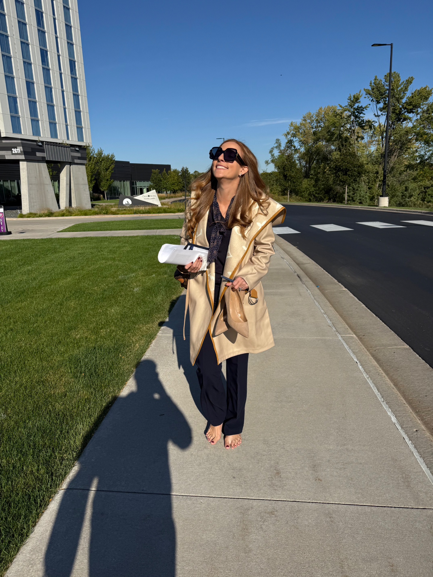 Erin Pash smiling on a sunny walk, shoes in hand