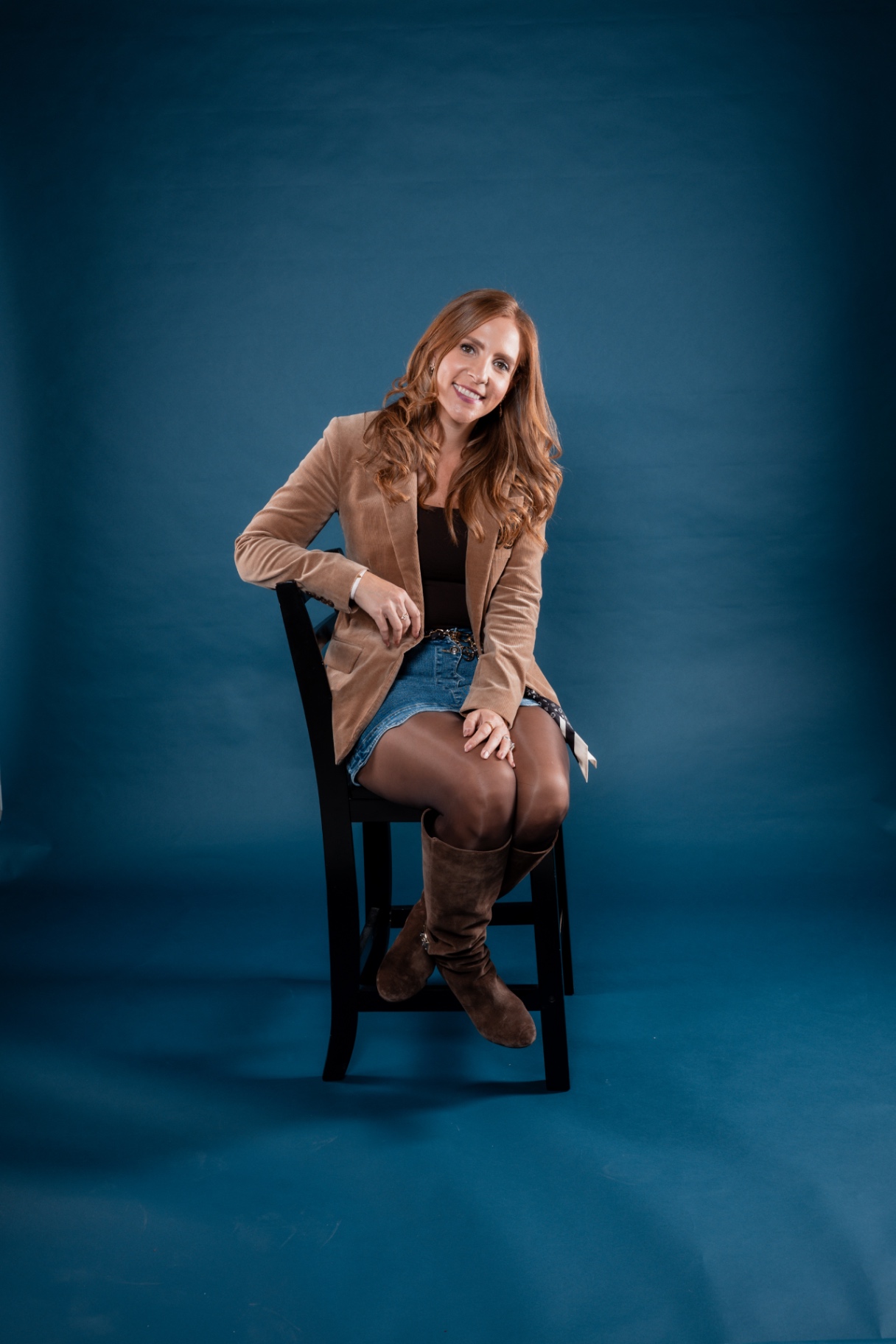 Erin Pash in a tan corduroy blazer on a teal-blue backdrop